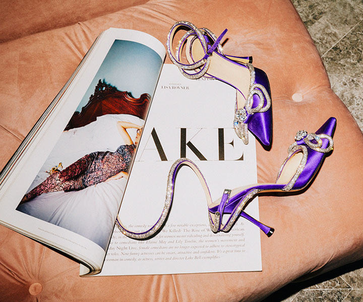 um par de elegantes sapatos de designer roxos sobre uma revista numa cadeira