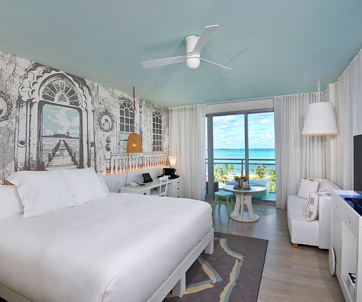 Ornate room with a king sized bed and view of azure waters