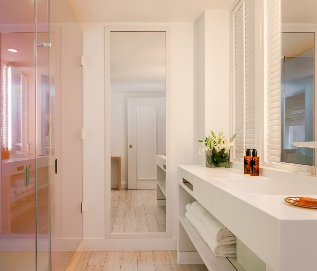 a bathroom with a sink vanity and pink tinted glass shower doors