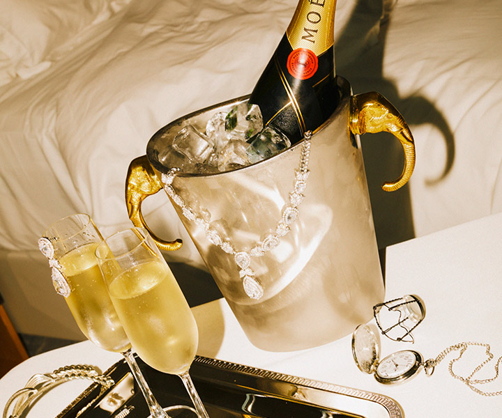 a bottle of champage in a bucket of ice with two full champagne glasses