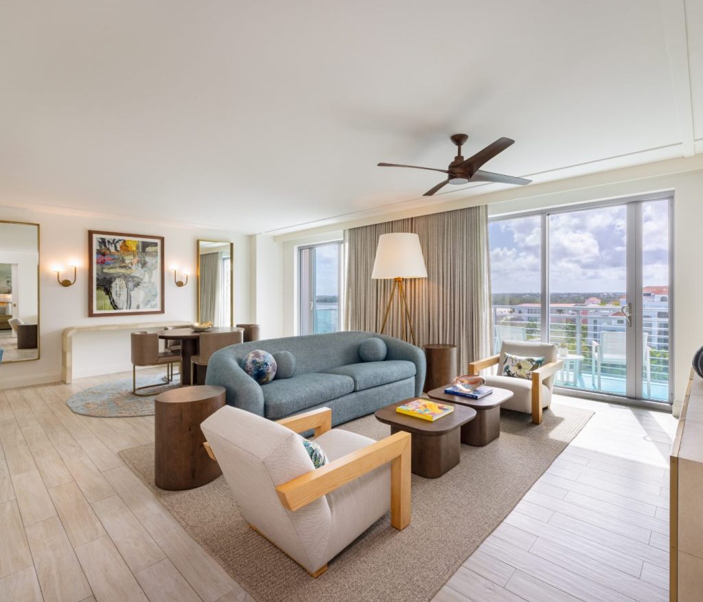 a living space with a blue couch and two white chairs facing a coffee table