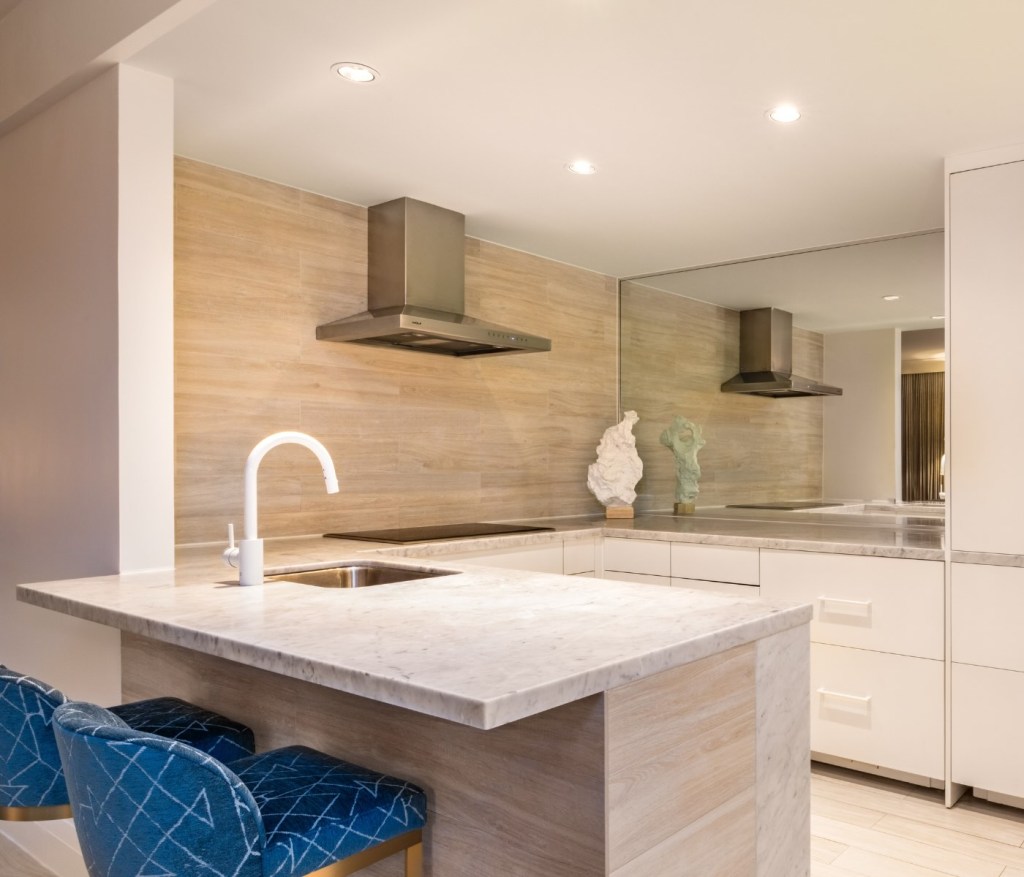 looking into the kitchen from the counter with two blue stools