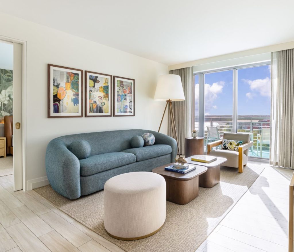 the living space with a blue couch and floor to ceiling windows 