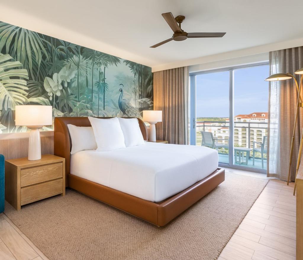 a king bed in a leather bed frame with tropical wallpaper and bedside tables