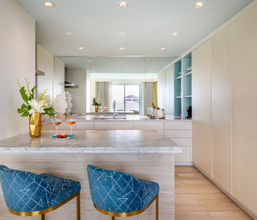 a kitchen counter with stools looking into the kitchen