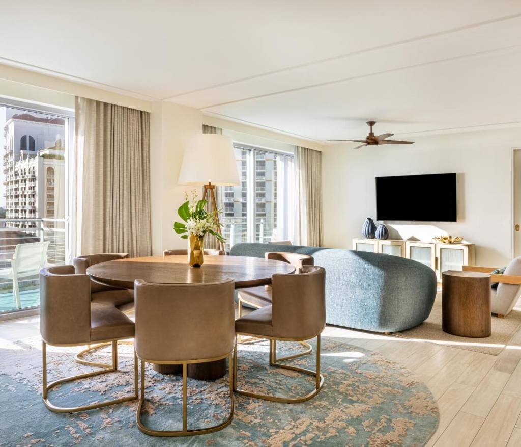 a dining table on a blue rug behind a blue couch and living space