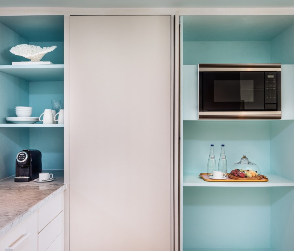 cabinets with a microwave, a coffee maker and cups