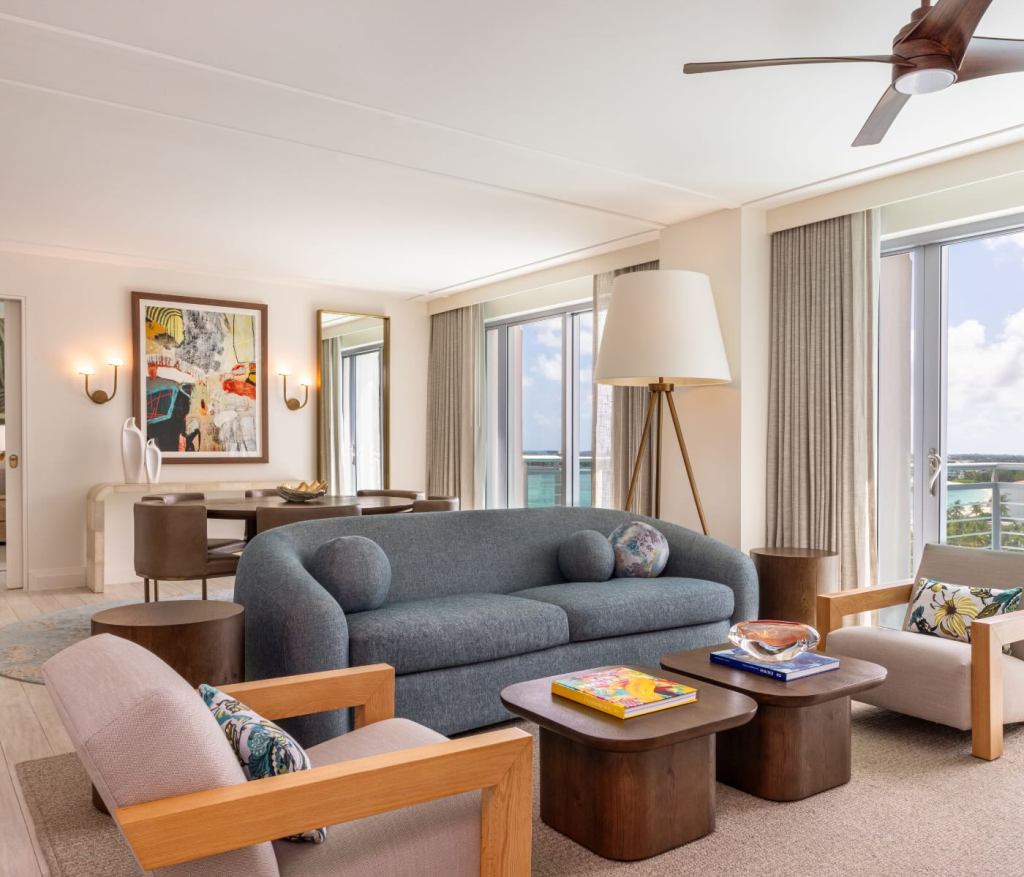 a living space with a blue couch, large floor lamp and two white chairs 