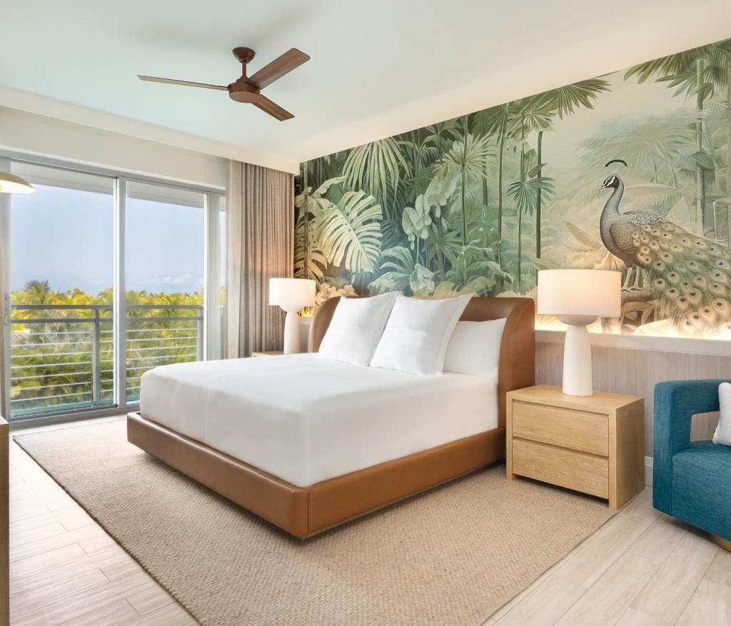 a king bed with a leather bed frame and tropical wallpaper behind it