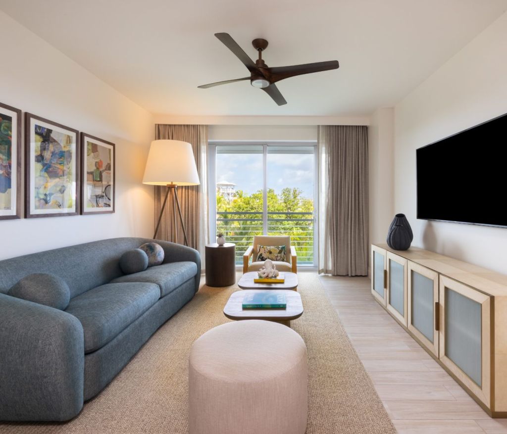 a living room with a blue couch, large lamp in the corner and hdtv