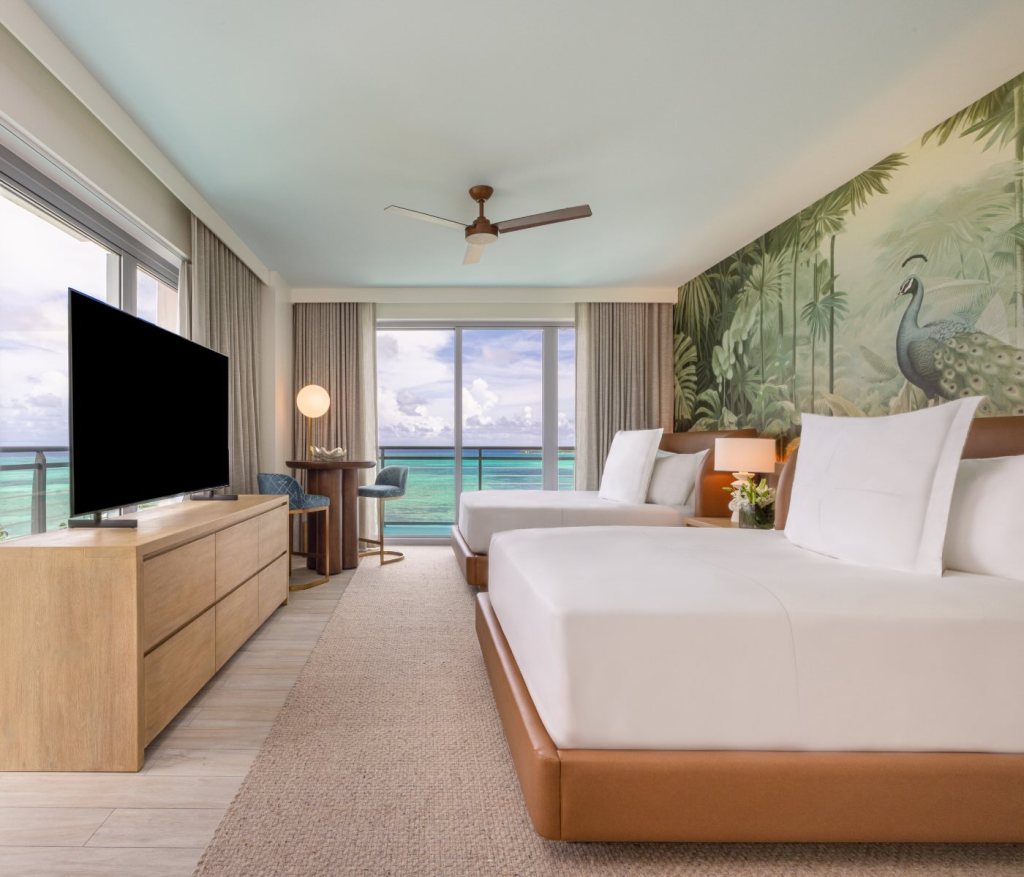 a side view of two queen beds with a dresser in front with an HDTV