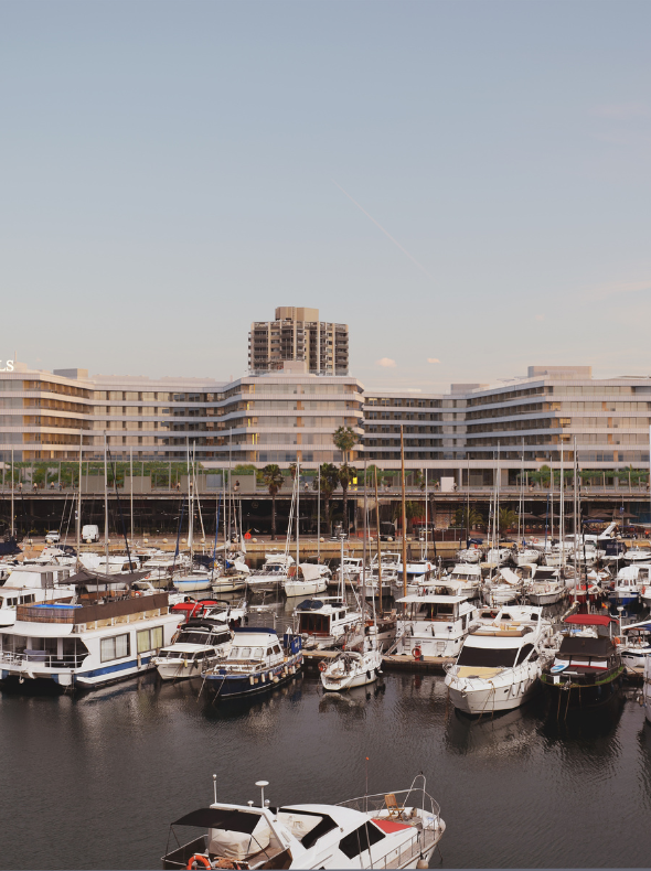 a beautifully designed hotel with a marina and sailboats in the foreground
