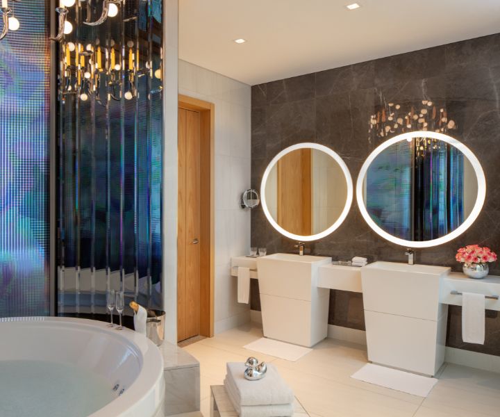 Bathroom with two round mirrors and a soaking tub in the SLS Dubai Presidential Suite.