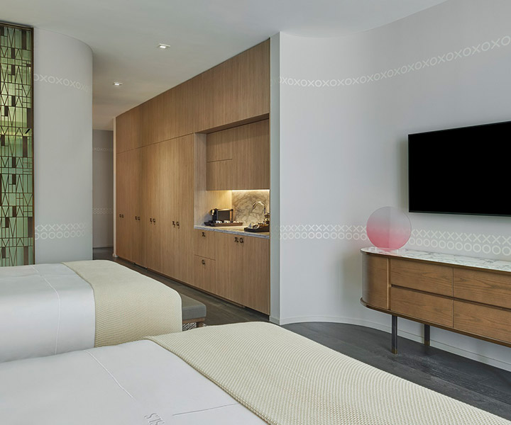 a two queen bedroom with a mounted HDTV and full minibar