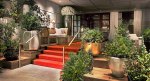 Entrance of the SLS Beverly Hills hotel with a red carpet and lush plants.