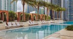 Outdoor pool at SLS LUX Brickell with lounge chairs and palm trees.