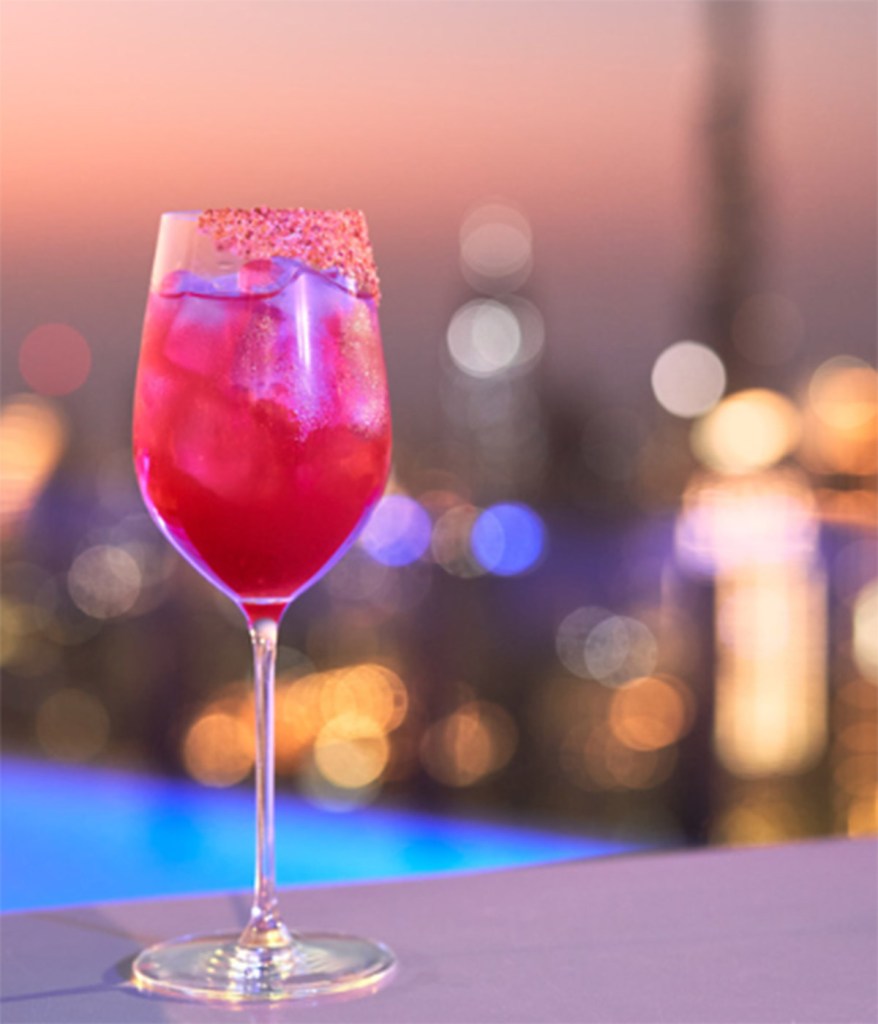 Pink cocktail at Privilege Dubai, on the 75th floor, with the city lights in the background