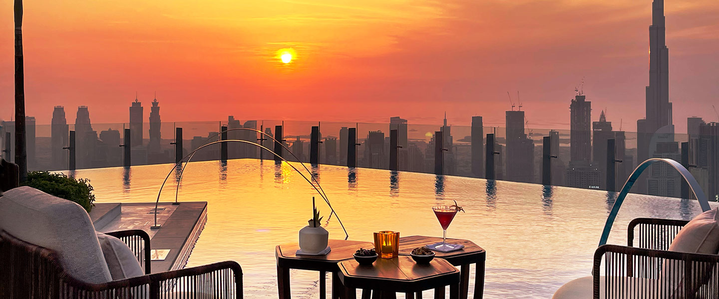 SLS Dubai 75th Floor rooftop pool at sunset, set with two chairs around a table with cocktails