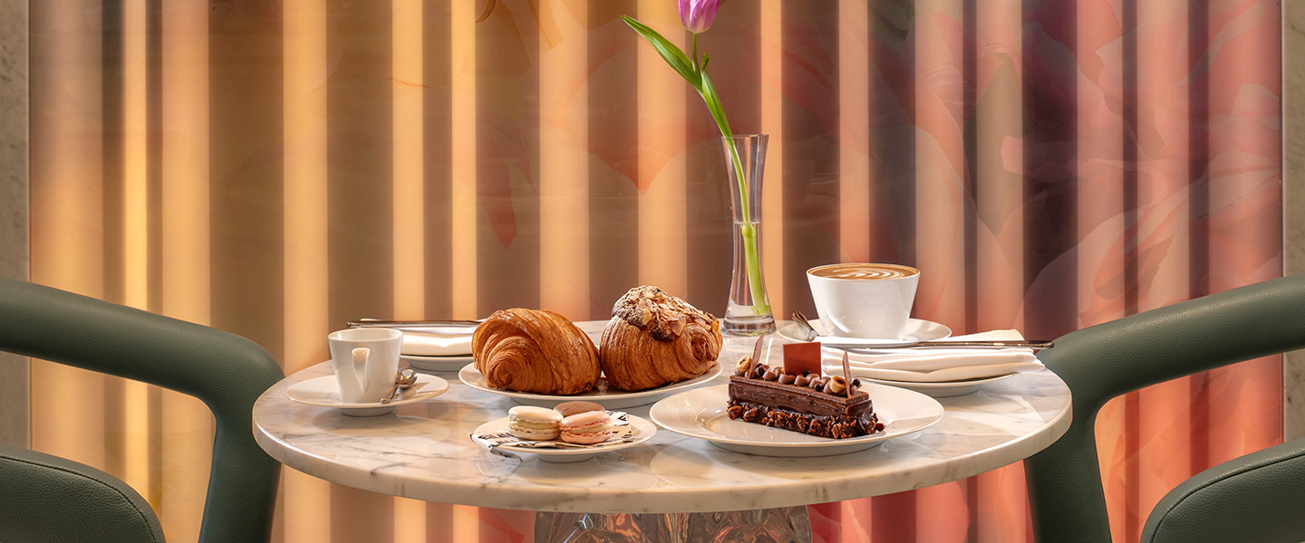 Cafe table set with pastries, coffee and a tulip in a vase
