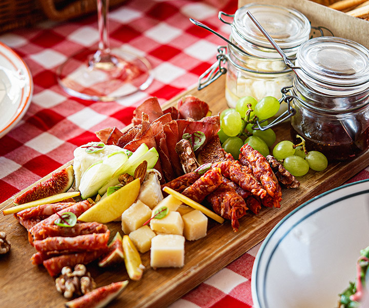 Un plateau de viandes, fromages et fruits sur une nappe à carreaux, servi lors d’un brunch au Fi’lia Dubai