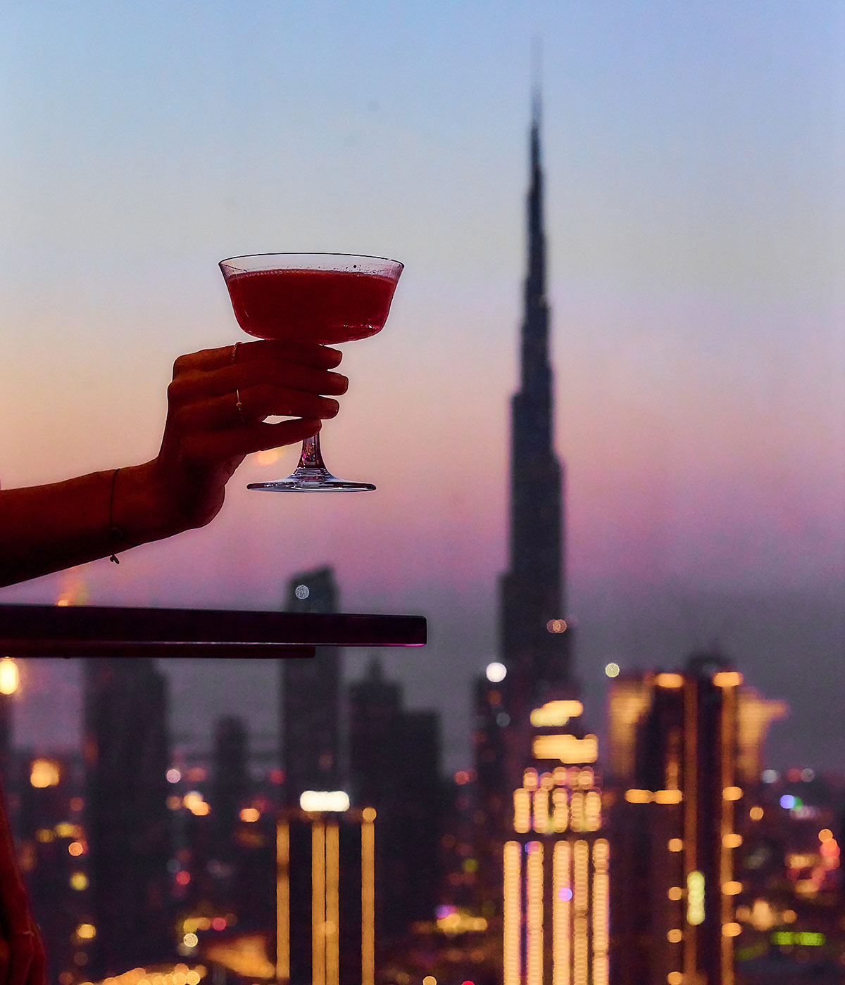 Cocktail being raised against the backdrop of the Dubai skyline