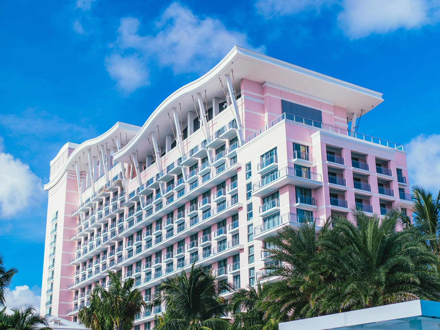 Exterior of a pink building, the SLS Baha Mar hotel, with blue skies in the background.