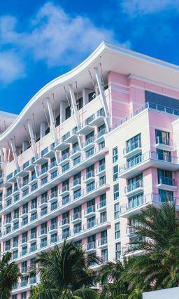 Exterior of a pink building, the SLS Baha Mar hotel, with blue skies in the background.