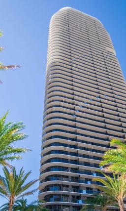 Modern white and glass skyscraper exterior of SLS LUX Brickell hotel with palm trees on the street.