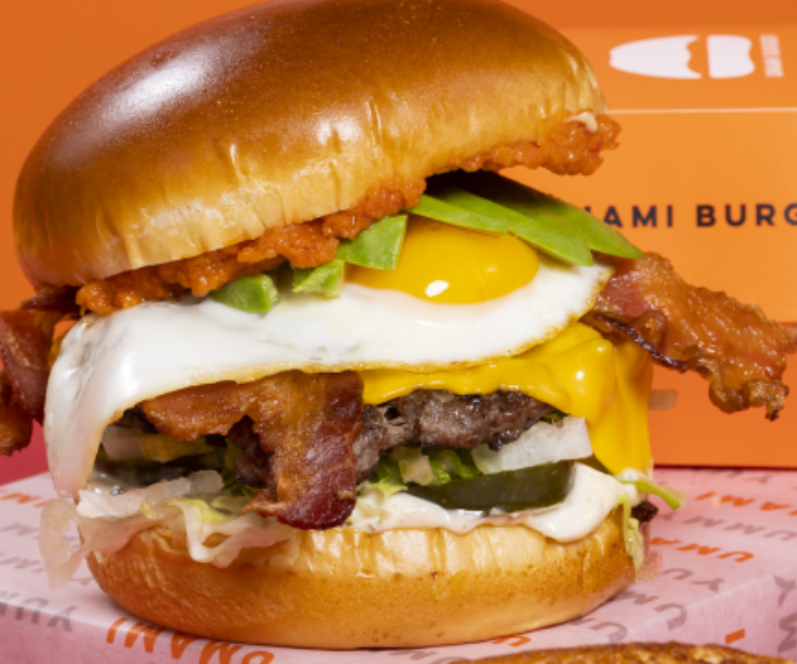 a large burger with egg, bacon, pickle, cheese and lettuce with a fluffy bun