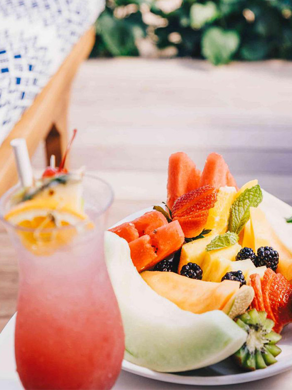 Um prato cheio de fruta fresca e uma bebida deliciosa, lindamente dispostos numa mesa.