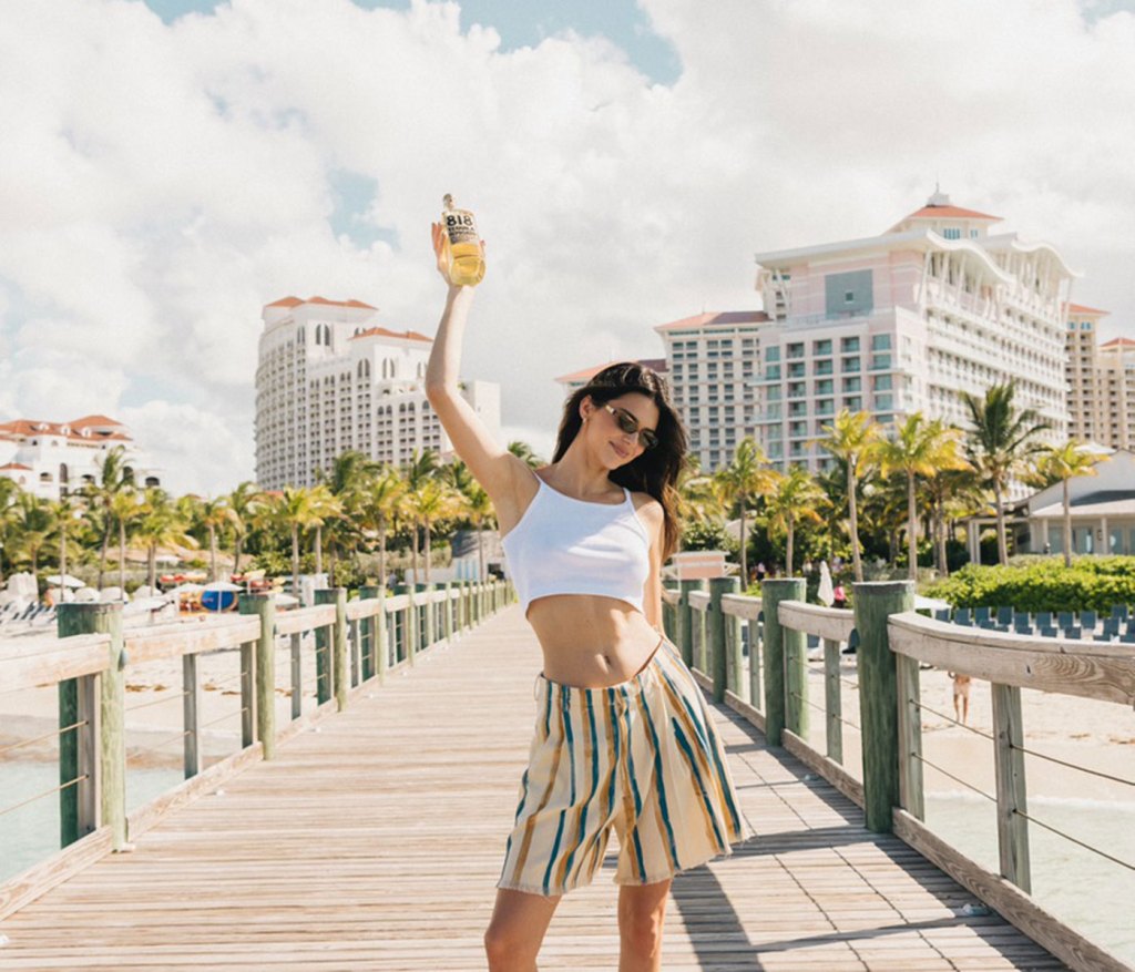 Kendall Jenner standing on a boardwalk at SLS Baha Mar, holding up her 818 tequila