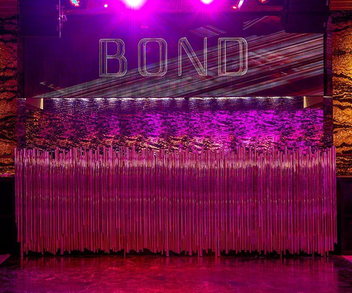 DJ booth illuminated with pink lighting at Bond Nightclub at SLS Baha Mar.