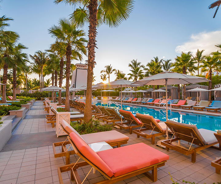 Pool area with sun loungers, umbrellas, and chairs basking in sunlight.