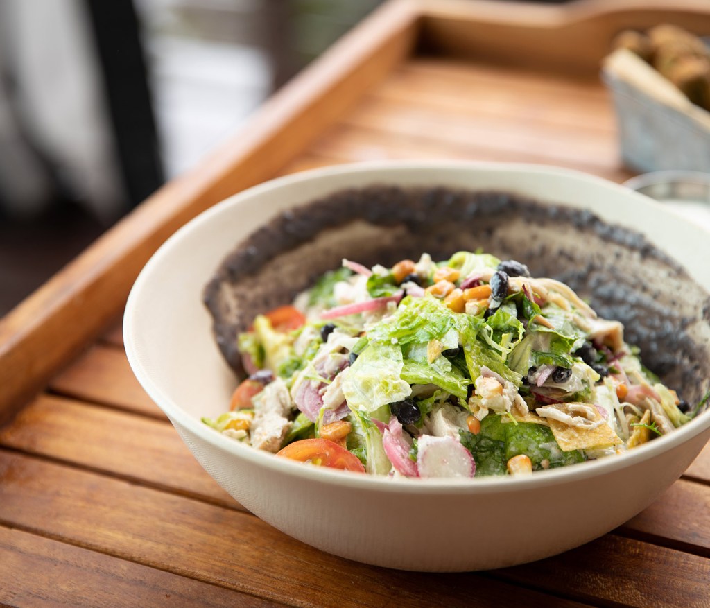 chopped salad in a bowl on a wooden table outdoors