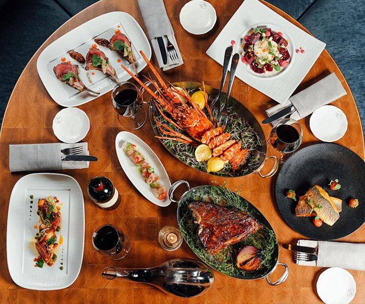 Indulgent spread of steak and seafood dishes on a round table at Carna Baha Mar restaurant.