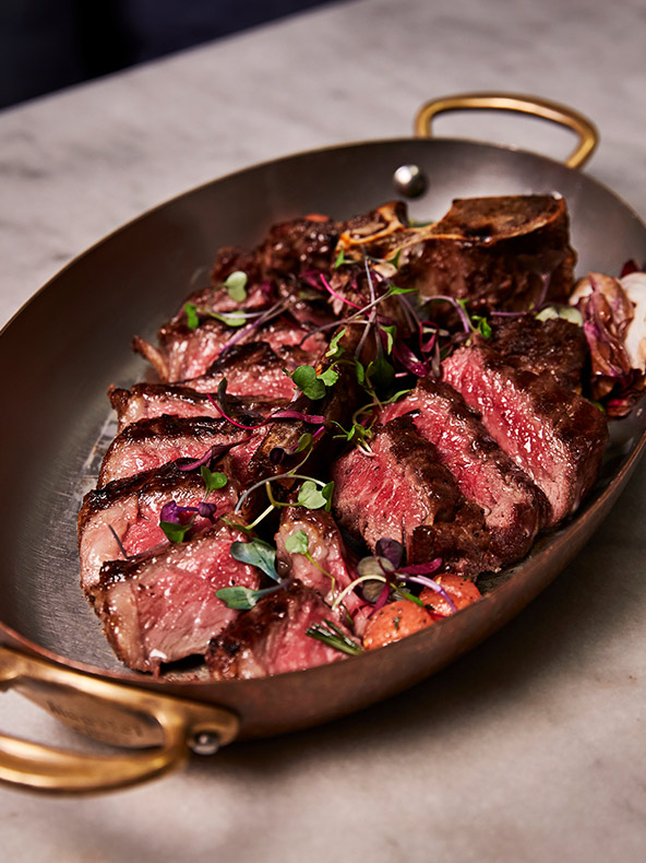 Bife mal passado perfeitamente preparado com guarnição verde numa frigideira oval.