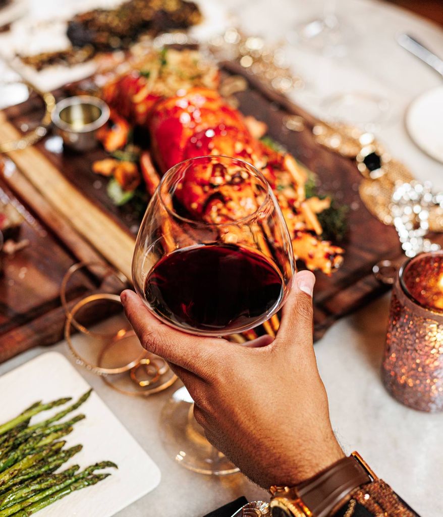 Glass of red wine, in front of a platter of lobster