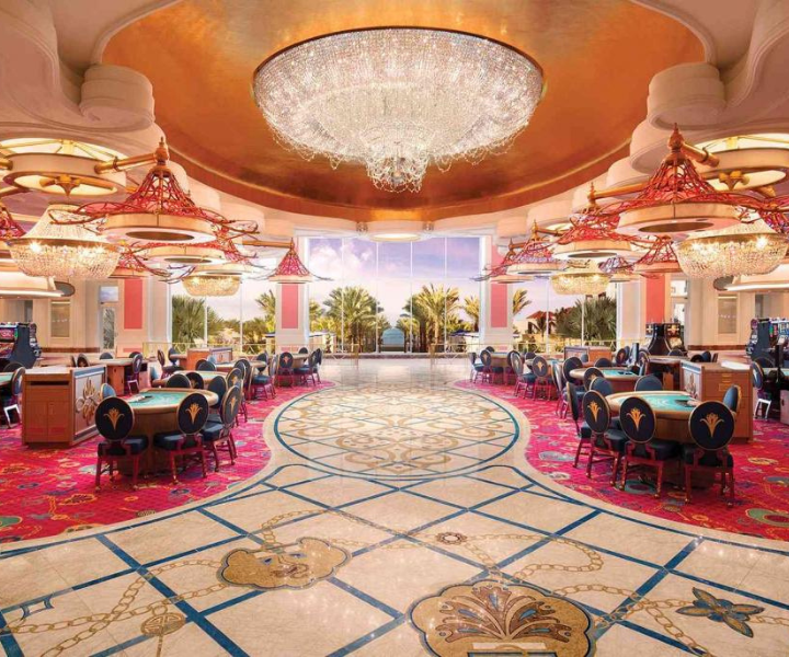 an ornate entrance with a spectacular crystal chandelier to a casino with gaming tables 