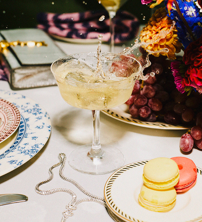 Splash in a beautiful cocktail glass on an ornately decorated table with flowers and macarons.