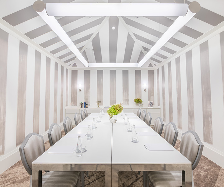 Sala de reuniões chique com uma grande mesa branca e cadeiras às riscas brancas e prateadas