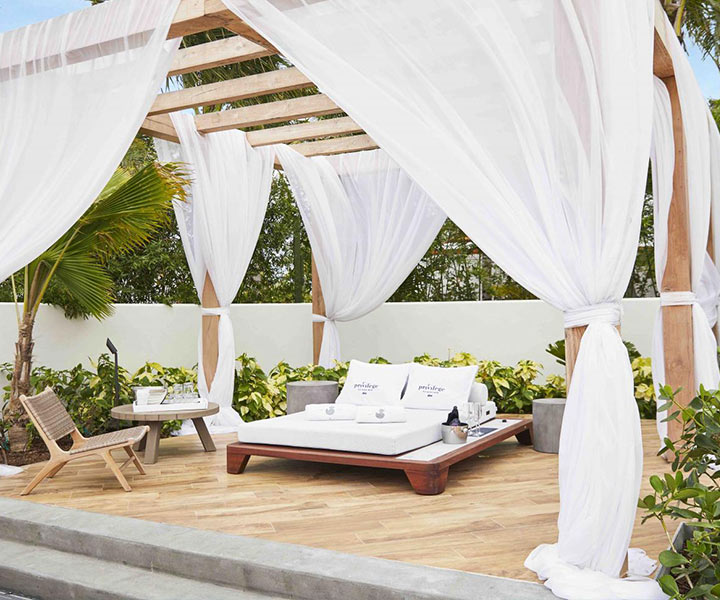 Cabaña en Privilege Pool en SLS Baha Mar, con un sofá cama blanco y cortinas blancas.