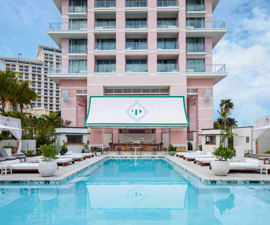 Privilege Pool at SLS Baha Mar, facade of a pink building with a large pool and lots of white lounge chairs.