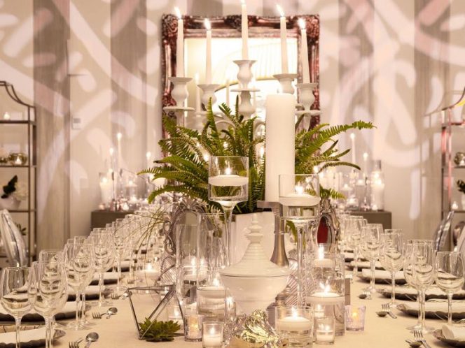 Uma mesa bem posta com velas acesas e uma jarra de flores, criando um ambiente romântico e elegante.