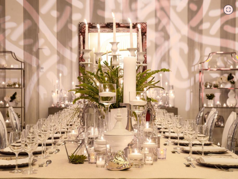 Une table joliment dressée avec des bougies allumées et des fleurs dans un vase, créant une ambiance romantique et élégante.