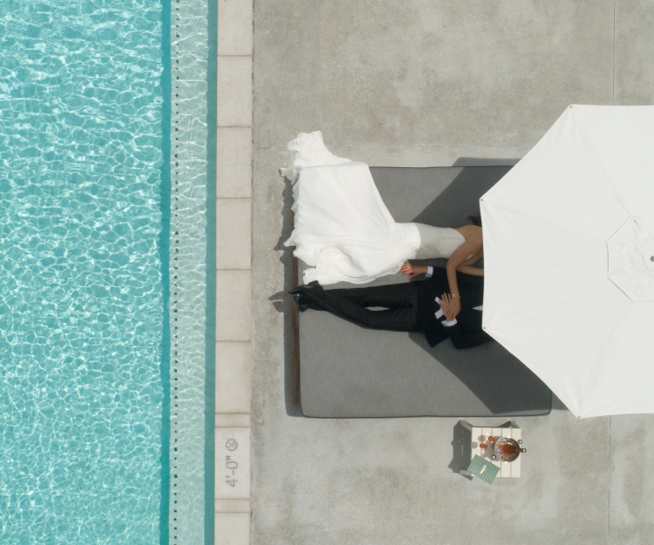 Noiva e noivo a relaxar debaixo do guarda-sol junto à piscina