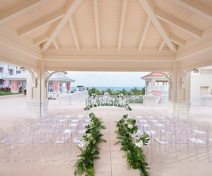 Un lieu prêt pour une cérémonie de mariage avec des chaises et de la verdure magnifiquement disposées, avec vue sur la mer