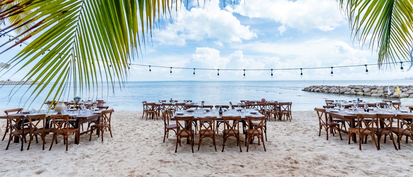 De longues tables dressées pour un événement sur la plage.