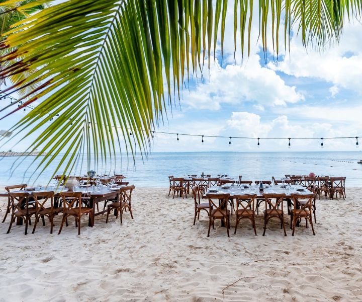 Long tables set up for an event on the beach. 