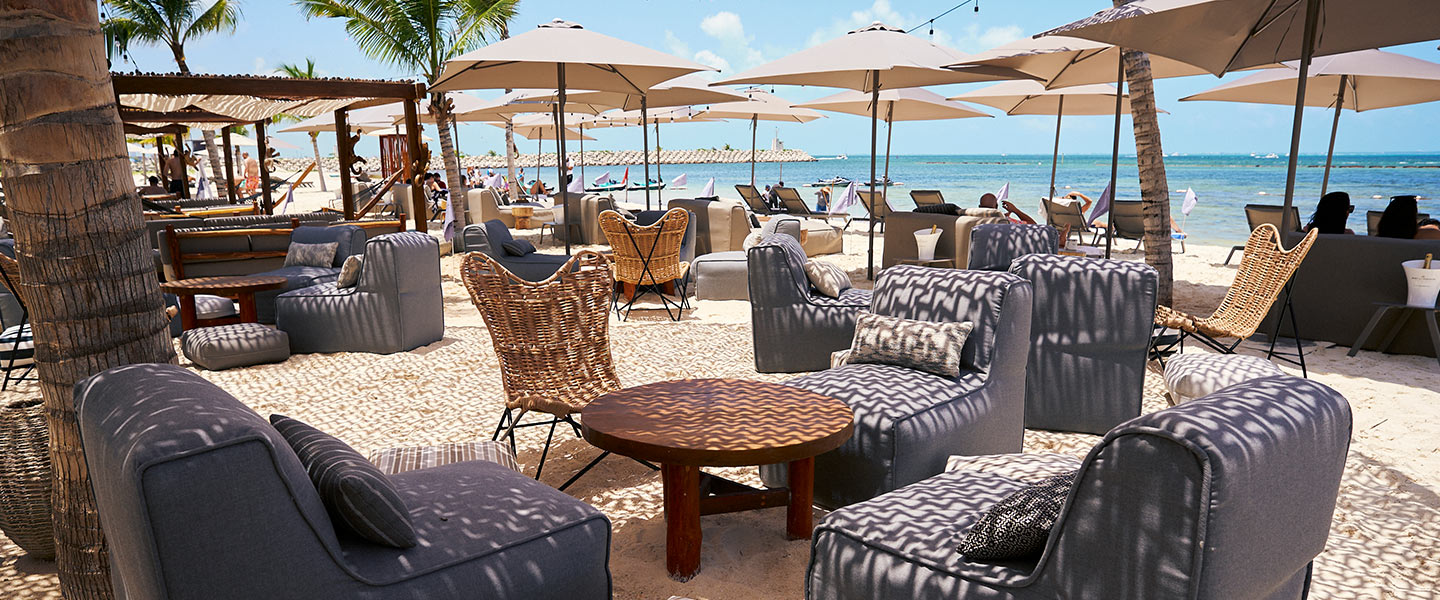 Scène de plage luxueuse avec des chaises élégantes et des parasols élégants sur du sable doré.