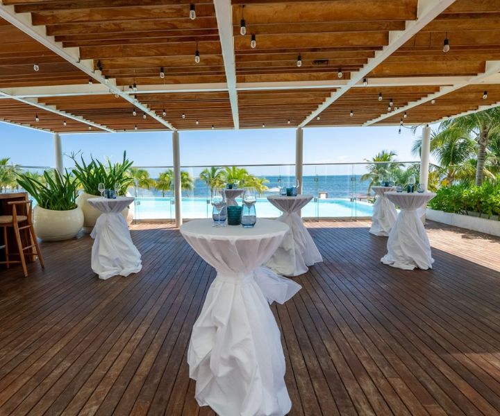 High tables draped in white table cloths overlooking the ocean 